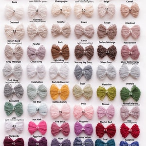May include: A chart of 60 yarn colors, organized in rows and columns. Each color is displayed as a looped bundle of yarn. The yarn colors include white, ivory, beige, camel, oatmeal, taupe, chestnut, rose brown, grey melange, cloud grey, light grey, stormy sky grey, silver grey, silver glitter grey, dark grey, eucalyptus, dark goldenrod, sage, pistachio, emerald, succulent, ice blue, cotton candy, pink, mauve, muted mauve, lilac, hot pink, fire brick, magenta, merlot red, red, burgundy, eggplant, plum, blue velvet, teal, sapphire, dark blue, colorful black, silver black, black glitter, and black.