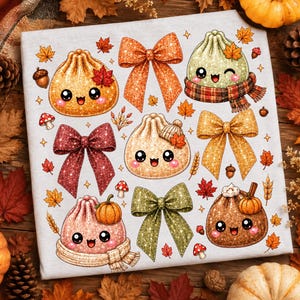 May include: A white fabric surface featuring a repeating pattern of glittery, cartoon-style dumplings with smiling faces, interspersed with various coloured bows, small pumpkins, acorns, mushrooms, and autumn leaves in shades of orange, red, and green.