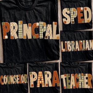 May include: A collection of black t-shirts featuring various job titles printed in large, block-style letters. Each letter is filled with a patchwork of autumn-themed patterns, including orange, brown, and green floral, plaid, and leopard prints.
