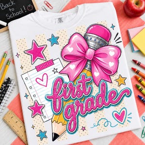 May include: A white t-shirt featuring a graphic print with the text first grade in pink glittery script. The design includes a large pink bow, a yellow pencil, a lined notebook page, pink and blue stars, and hearts on a beige striped background.