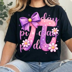 May include: Black t-shirt featuring a large, colorful Pi symbol design. The design includes a purple bow, pink and purple text, and daisy accents. The words "Pi Day" are incorporated into the design.