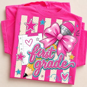 May include: A bright pink t-shirt featuring a graphic print of a yellow pencil with a large pink bow, a piece of lined notebook paper with a heart, and the text "first grade" in glittery pink script. The design includes pink and blue stars.