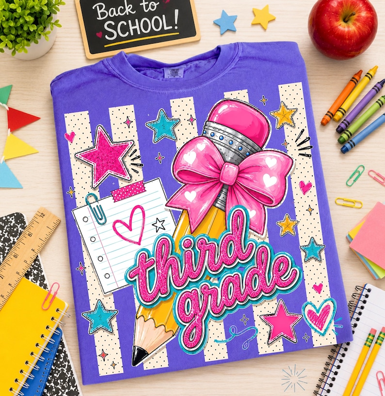 May include: A purple t-shirt featuring a graphic of a yellow pencil with a large pink bow, a lined notepad with a heart, and the text third grade in pink script. The design includes various colourful stars and dots on a striped background.