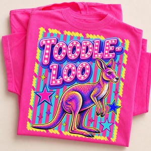 Op de afbeelding: Een felroze t-shirt met een kleurrijke kangoeroe-illustratie en de woorden "TOODLE LOO" in een marquee-lettertype. Het ontwerp bevat sterren en een gestreepte achtergrond, wat een speelse en levendige uitstraling creëert.