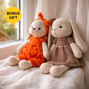 Pode incluir: Dois bonecos de coelho de crochê feitos à mão com corpos de fio cor de creme. Um coelho usa um macacão laranja texturizado com uma faixa combinando, enquanto o outro usa um vestido marrom. Um emblema amarelo em forma de estrela diz BONUS GIFT.