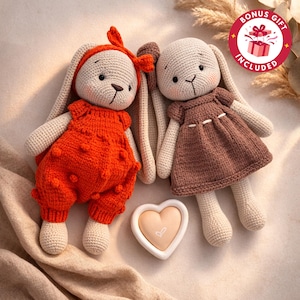 Op de afbeelding: Twee gehaakte konijnenpoppen. Eén konijn draagt een oranje romper en haarband, de ander een bruine jurk. Een hartvormig speeltje staat ertussen. De poppen hebben lange oren en zijn gemaakt van beige en oranje garen. Een bonuscadeau is inbegrepen.