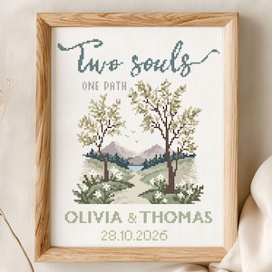 Puede incluir: Un patrón de punto de cruz enmarcado con el texto "Two souls, One Path". La obra de arte representa un paisaje con árboles, un camino y montañas. Los nombres "Olivia & Thomas" y la fecha "28.10.2026" están debajo. El patrón es para una boda.