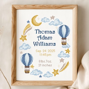 Può includere: Uno schema a punto croce incorniciato con un tema celeste in blu e oro, con mongolfiere, stelle, nuvole e una luna crescente. Il testo riporta Thomas Adam Williams, 24 set 2025, 23:45, 3827 g e 53 cm.