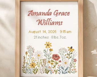 May include: A framed cross-stitch birth announcement featuring the name Amanda Grace Williams, the date August 14, 2026, the time 9:15 am, and the measurements 21 inches and 8 lbs. 7 oz. above a colorful embroidered field of various wildflowers.