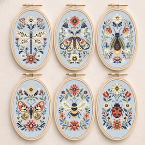 Peut inclure: Six tambours à broder ovales présentant des motifs au point de croix de libellule, papillon de nuit, luciole, papillon, bourdon et coccinelle entourés de fleurs sur tissu bleu clair. Texte : Instant Download, 15 DMC colors, 100x70 stitches.