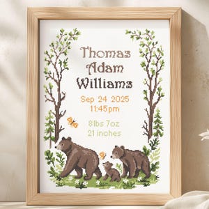 May include: A framed cross-stitch birth announcement featuring the text Thomas Adam Williams, Sep 24 2025, 11:45 pm, 8 lbs 7oz, and 21 inches. The design includes two brown bears and a cub, green trees, and orange butterflies in a forest scene.