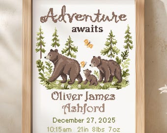 May include: A framed cross-stitch art piece featuring a forest scene with three brown bears, green pine trees, and orange butterflies. The text reads Adventure awaits, Oliver James Ashford, December 27, 2025, 10:15am, 21in, 8lbs 7oz.