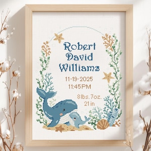 May include: Cross-stitch artwork in a wooden frame featuring a whale and baby whale design. The artwork includes the name "Robert David Williams", date, time, weight (8lbs. 7oz.), and length (21 in.) surrounded by sea-themed elements.