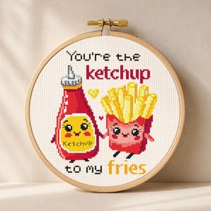 May include: Cross-stitch hoop art featuring a red ketchup bottle and a box of fries, both with smiling faces. The text reads "You're the ketchup to my fries." The design is set against a neutral background.