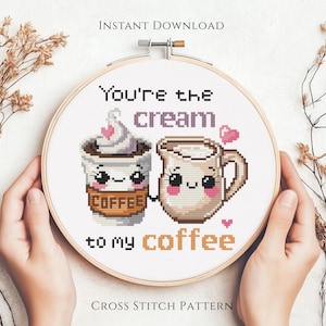 May include: Cross-stitch design in a wooden hoop with coffee-themed characters. The text says "You're the cream to my coffee." The design includes a coffee cup with whipped cream and a milk jug, both with smiling faces and small pink hearts.