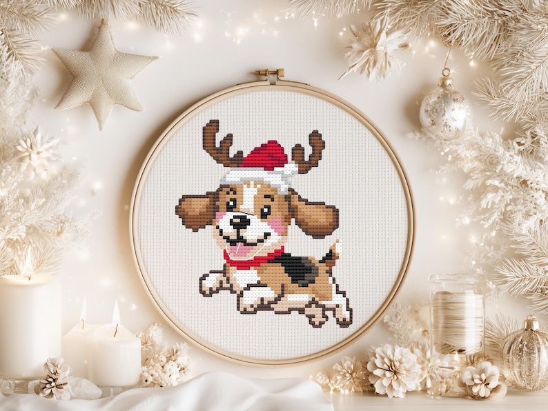 May include: A cross-stitch pattern in a round wooden embroidery hoop featuring a brown, white, and black beagle puppy wearing a red and white Santa hat and a red collar. The puppy is depicted in a running pose against a white fabric background.