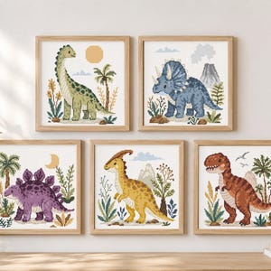 May include: Five square framed cross-stitch artworks featuring prehistoric dinosaurs. The collection includes a green long-necked dinosaur, a blue triceratops, a purple stegosaurus, a yellow parasaurolophus, and a brown tyrannosaurus rex.