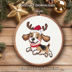 May include: A cross stitch pattern in a wooden embroidery hoop featuring a cartoon beagle dog wearing a red and white Santa hat with reindeer antlers, a red collar, and a black and brown coat, set against a white fabric background.