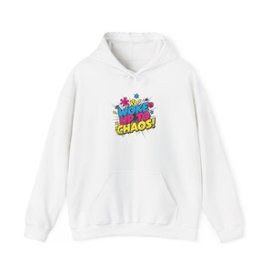 May include: White hoodie with a front pocket and drawstring hood. The front features a colourful graphic that reads "WOKE UP TO CHAOS!" in a comic book style with yellow, blue, pink, and green accents. The hoodie is made of a soft material.