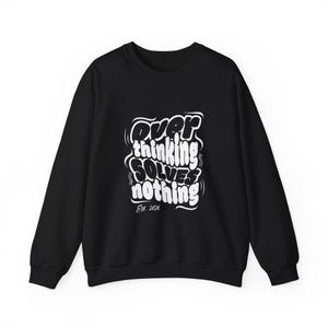 Puede incluir: Sudadera negra de cuello redondo con el texto blanco "Overthinking Solves Nothing" en una fuente estilizada. El texto incluye el año "Est. 2026" debajo. La sudadera tiene mangas largas y cuello redondo.