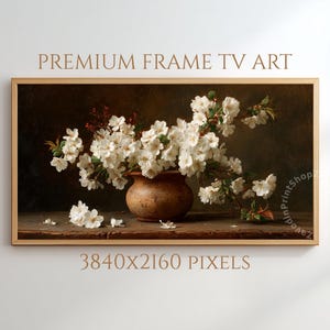 Puede incluir: Una impresi&oacute;n art&iacute;stica digital enmarcada que presenta una naturaleza muerta de flores blancas en un jarr&oacute;n de cer&aacute;mica marr&oacute;n. La obra de arte tiene un fondo oscuro y est&aacute; etiquetada como "PREMIUM FRAME TV ART" y "3840X2160 PIXELS".