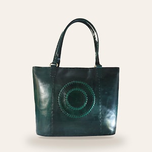The Rambagh Tote in deep green full-grain leather, three-quarter view showing the concentric hand-stitched circle motif and its structured depth