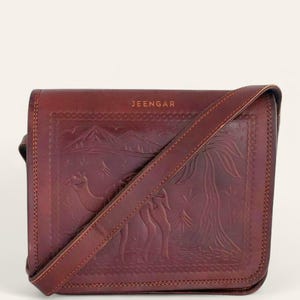The Jaisalmer Sling in Cherry, front view with the strap laid across the embossed flap