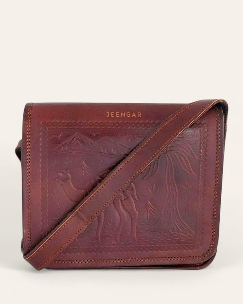The Jaisalmer Sling in Cherry, front view with the strap laid across the embossed flap