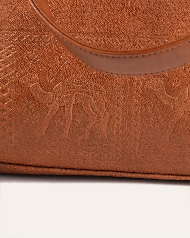 Close view of the hand-tooled camel caravan imprint on the lower front of The Abhaneri Tote