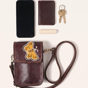 The Nagaur Kashidakari Sling shown with a smartphone, card holder, keys and lip balm to show what it holds (AI-generated)