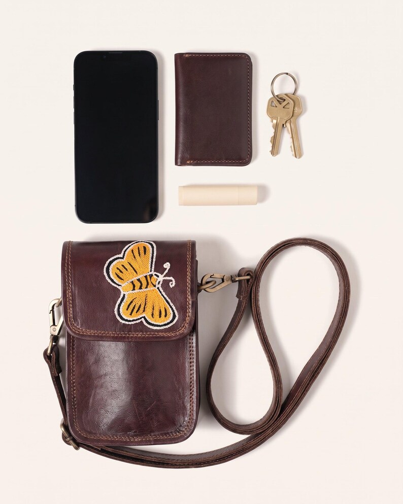 The Nagaur Kashidakari Sling shown with a smartphone, card holder, keys and lip balm to show what it holds (AI-generated)