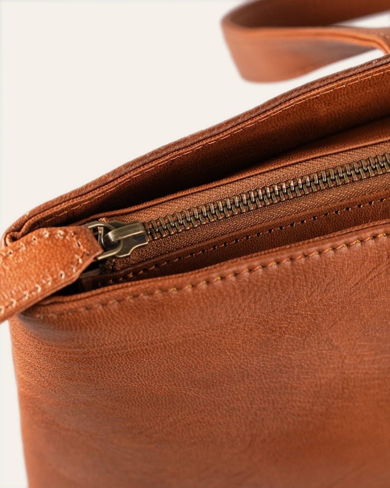 The full-width antique-finish metal top zip and leather pull of The Abhaneri Tote