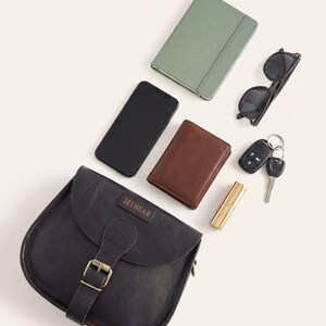 What The Marwari Sling in Black holds: a phone, wallet, keys, notebook, sunglasses and lipstick laid out beside the bag (AI-generated)