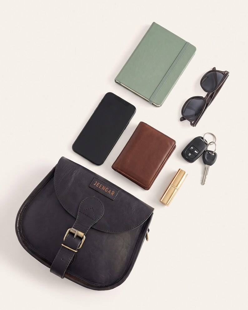 What The Marwari Sling in Black holds: a phone, wallet, keys, notebook, sunglasses and lipstick laid out beside the bag (AI-generated)