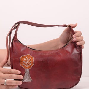 The Kashida Shoulder Bag Padmini in Cherry held in hand