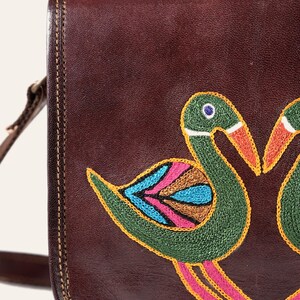 Close-up of the hand-embroidered birds on the Moruda Sling, green, turquoise and rose chain stitch