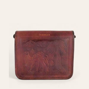 The Jaisalmer Sling in Cherry, hand-embossed camel and palm scene on full-grain leather, front view