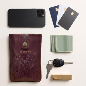 The Osian Mobile Sling shown with a phone, three cards, folded notes, keys and a lipstick to show what it holds (AI-generated)