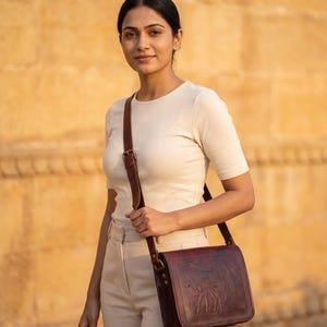 The Jaisalmer Sling in Cherry worn cross-body against golden sandstone at golden hour (AI-generated)
