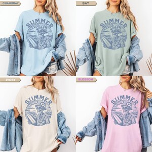 May include: Four t-shirts in different colors: light blue, green, ivory, and pink. Each shirt features a circular graphic with the words "Summer Time" and a skeleton with a surfboard. The shirts are casual and have rolled-up sleeves.
