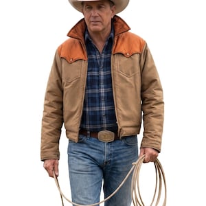 May include: A beige cowboy hat, a tan jacket with orange shoulder yokes, a blue and black plaid button-down shirt, blue denim jeans, and a brown belt with a large metallic buckle. A coiled rope is held in one hand against a white background.