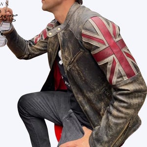 May include: A distressed brown leather jacket featuring a Union Jack flag design on the right shoulder. The jacket has a zip closure and a worn, vintage appearance. The text "CROWN CRAFT JACKETS" is visible in the upper left corner.