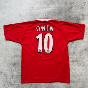 May include: A red short-sleeved sports jersey featuring the name OWEN and the number 10 printed in white with black outlines on the back. The jersey has a white collar detail and small lion emblems integrated into the number 10 graphic.