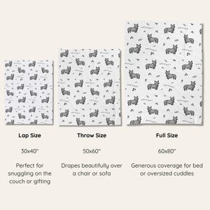 May include: White blankets with a repeating black corgi dog pattern, available in lap (30x40 inches), throw (50x60 inches), and full (60x80 inches) sizes. The blankets feature the text "wild at heart".