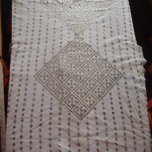 Puede incluir: Tela blanca con un patrón geométrico plateado. El patrón está formado por pequeños cuadrados y diamantes.