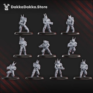 May include: Nine grey miniature figurines of futuristic soldiers, each posed differently, mounted on black bases. The figures are detailed with armour and weapons, suggesting a science fiction or tabletop gaming theme. The DakkaDakka.Store logo is in the top left corner.