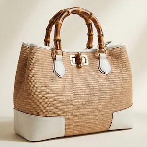 Pode incluir: Bolsa de m&atilde;o bege tecida com al&ccedil;a de bambu e detalhes em couro branco. A bolsa tem formato retangular, ferragens douradas e fecho seguro. A base da bolsa &eacute; branca.