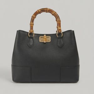 May include: A black leather handbag featuring a textured surface, a curved bamboo handle, and a gold-toned metal turn-lock closure. The bag has a structured base and is attached to the handle with gold-toned metal rings and leather tabs.