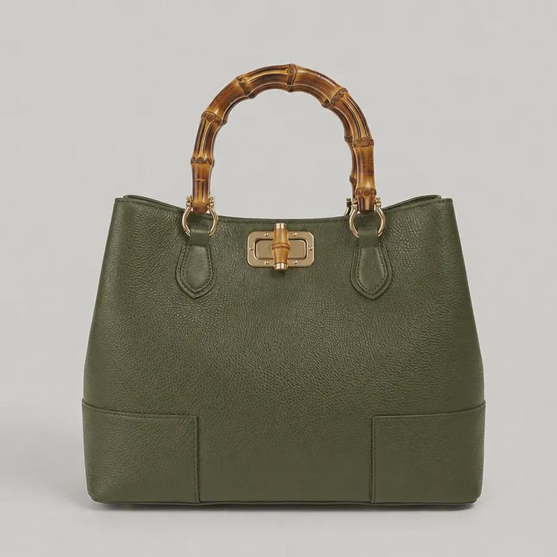 May include: An olive green handbag with a textured surface, featuring a curved bamboo handle and a gold-toned metal turn-lock closure with a bamboo accent. The bag has a structured base and gold hardware connecting the handle to the body.