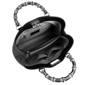 May include: A black leather handbag with a textured surface and two curved bamboo handles. The interior is lined with grey fabric and features a central zippered compartment, two open slip pockets, and a small zippered wall pocket.